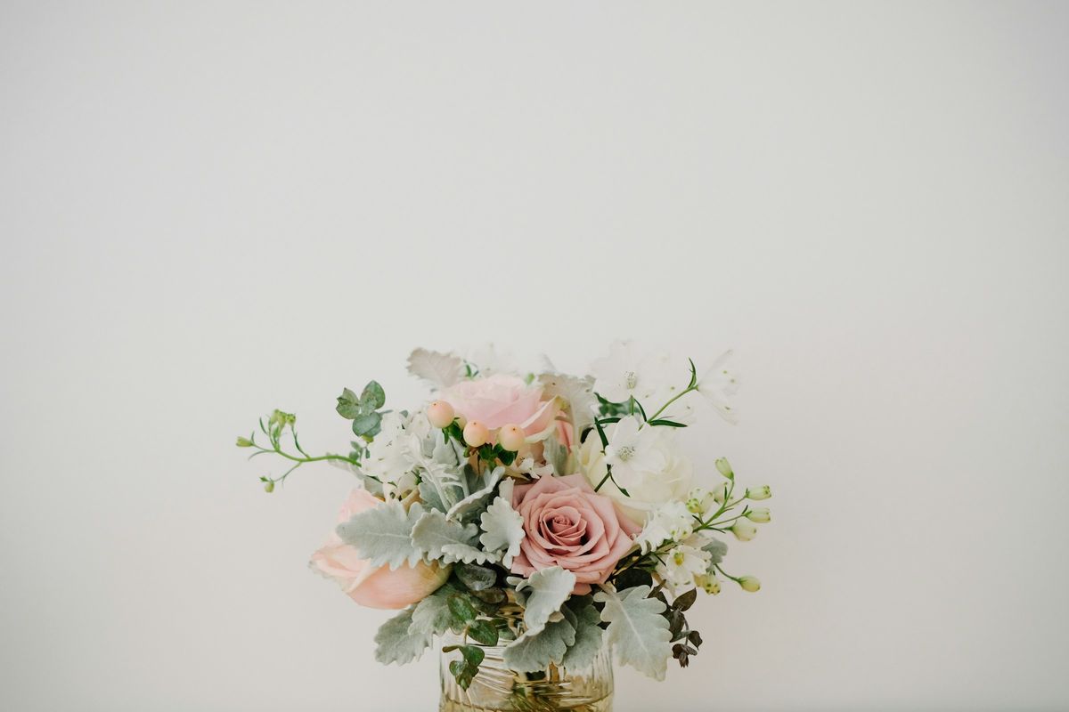 Soft pink rose and greenery arrangement against a plain light wall