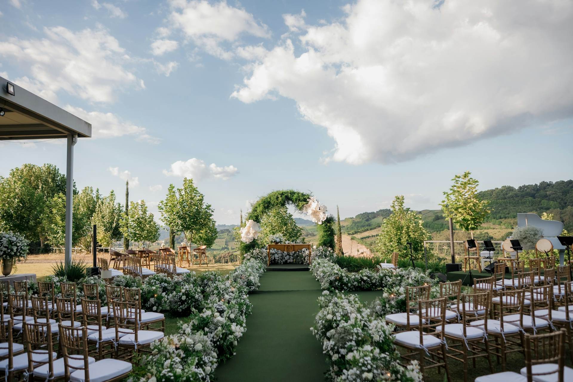 Outdoor ceremony aisle lined with white chairs and greenery